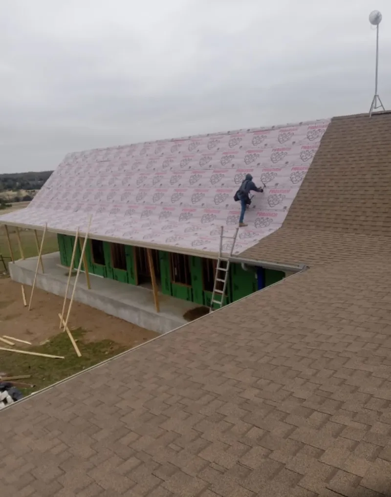 Worker preparing underlayment for a metal roof installation in Fraser